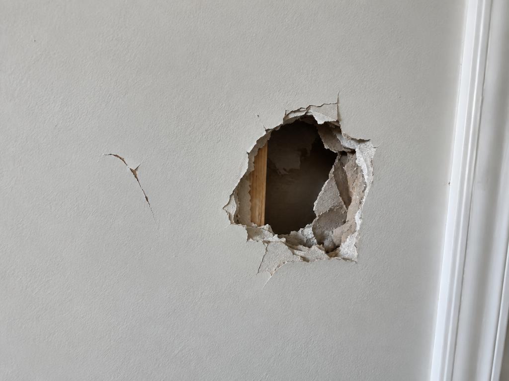 Damaged drywall with a hole and crack before repair